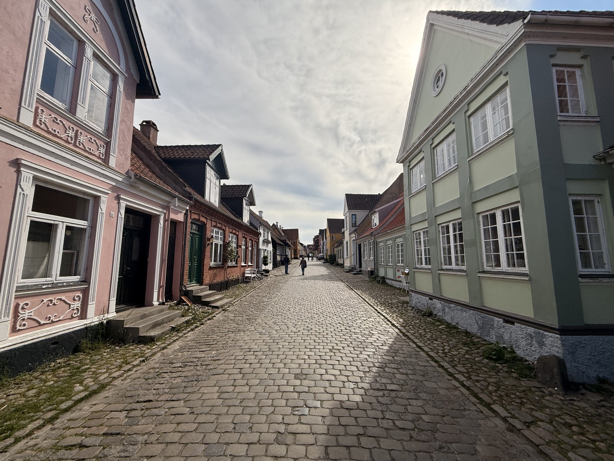 Kopfsteinpflastergasse in Ærøskøbing mit rosa und mintgrünen Häusern