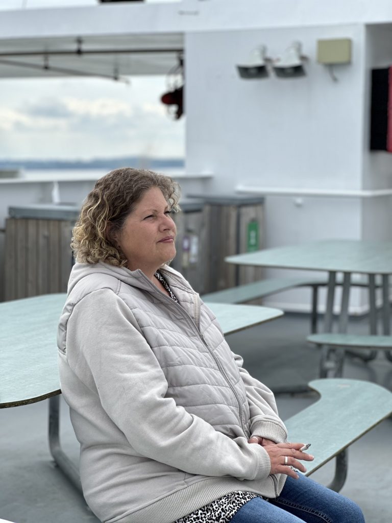 Tanja in dicker Jacke an den Picknicktischen auf dem Fährdeck