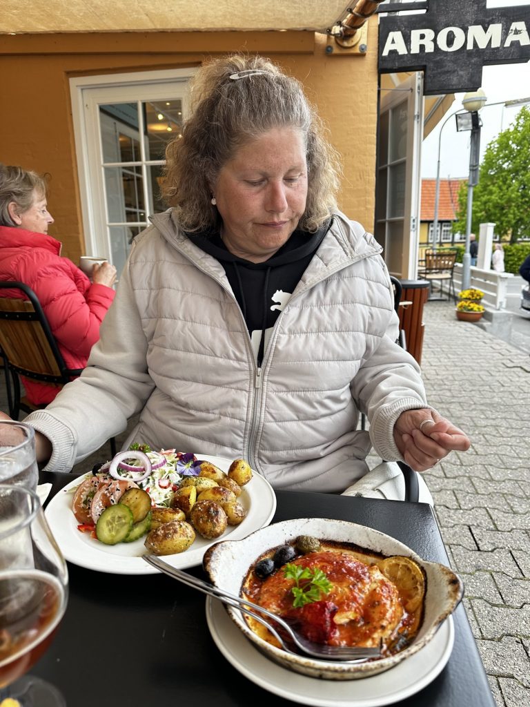 Tanja vor dem Restaurant Aroma mit einem überbackenen Gericht im Tontopf