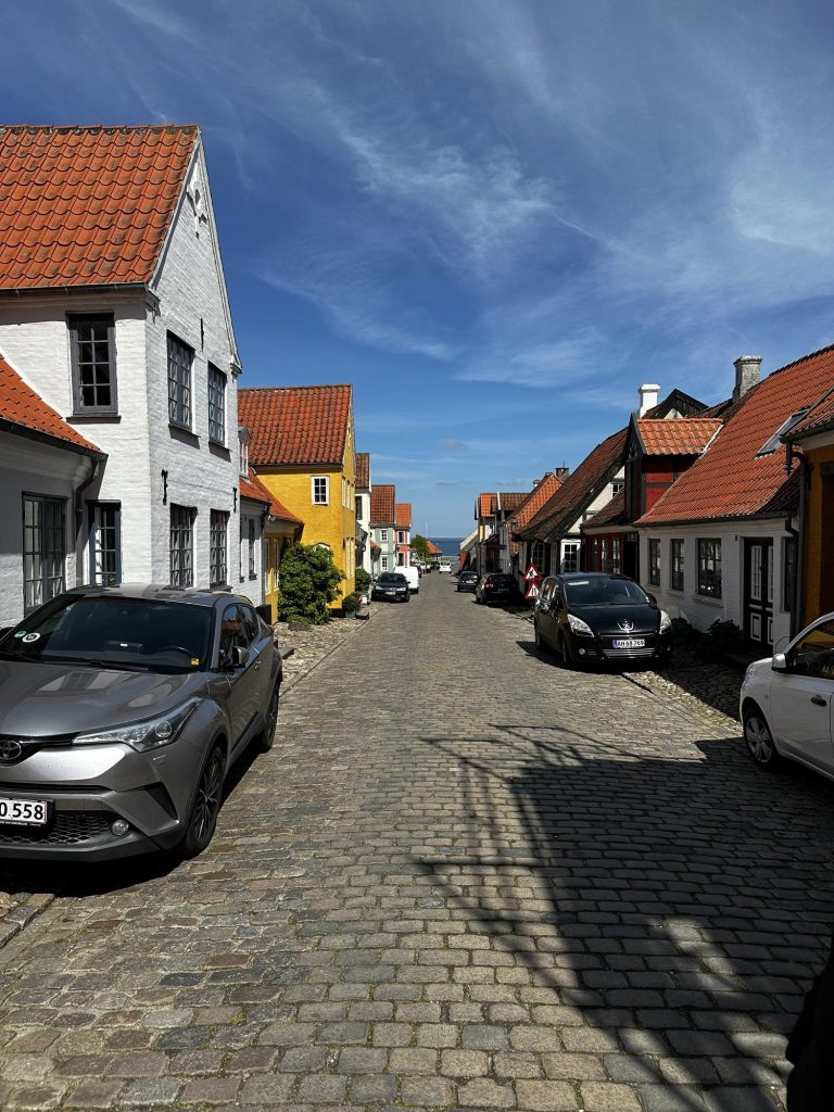 Blick durch eine Gasse auf ein senfgelbes Haus