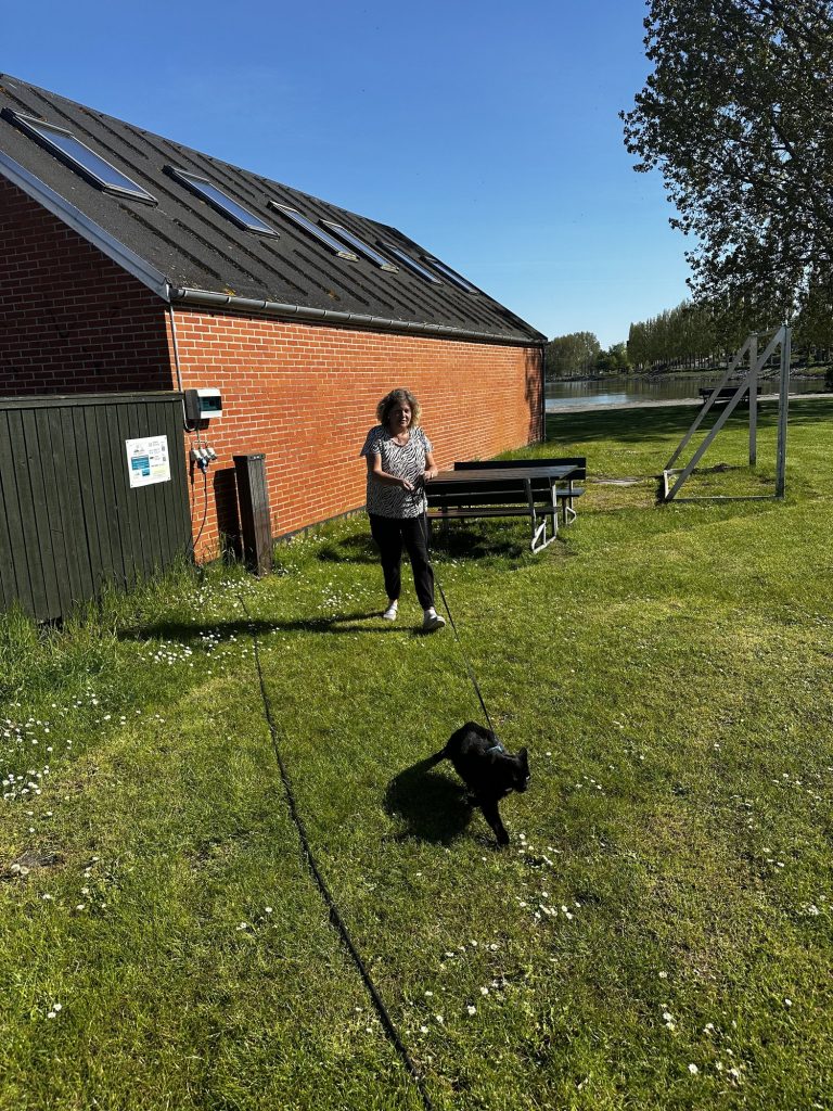 Tanja mit Kater Krümel an der Leine vor dem Sanitärgebäude