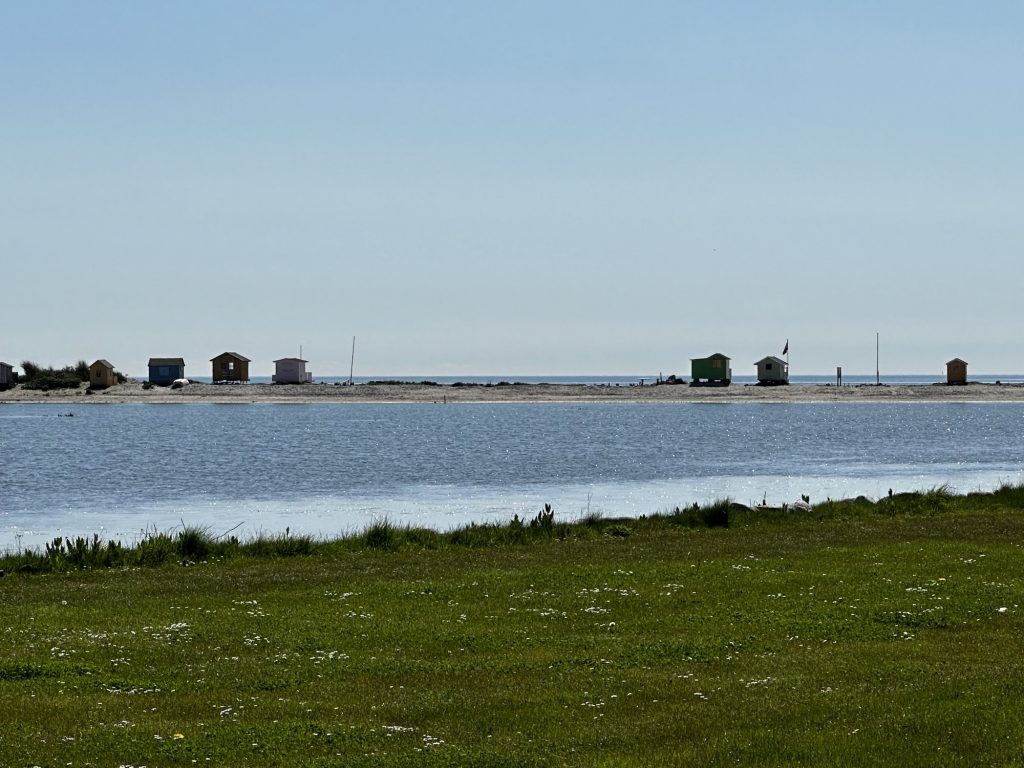 Blick über das Wasser auf die bunten Badehäuschen auf der Nehrung Eriks Hale