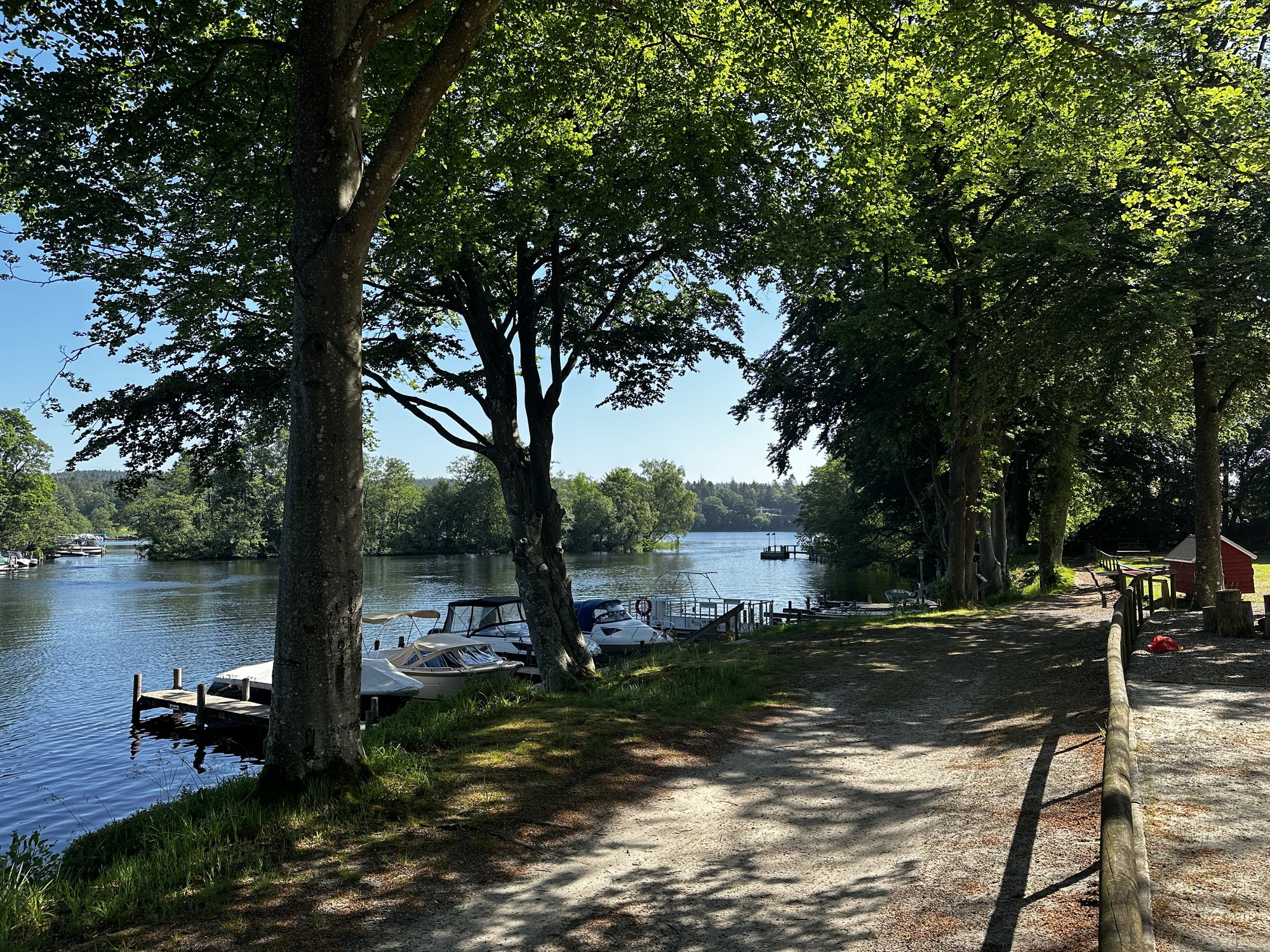 Bootssteg mit Motorbooten im spiegelglatten Wasser am Morgen