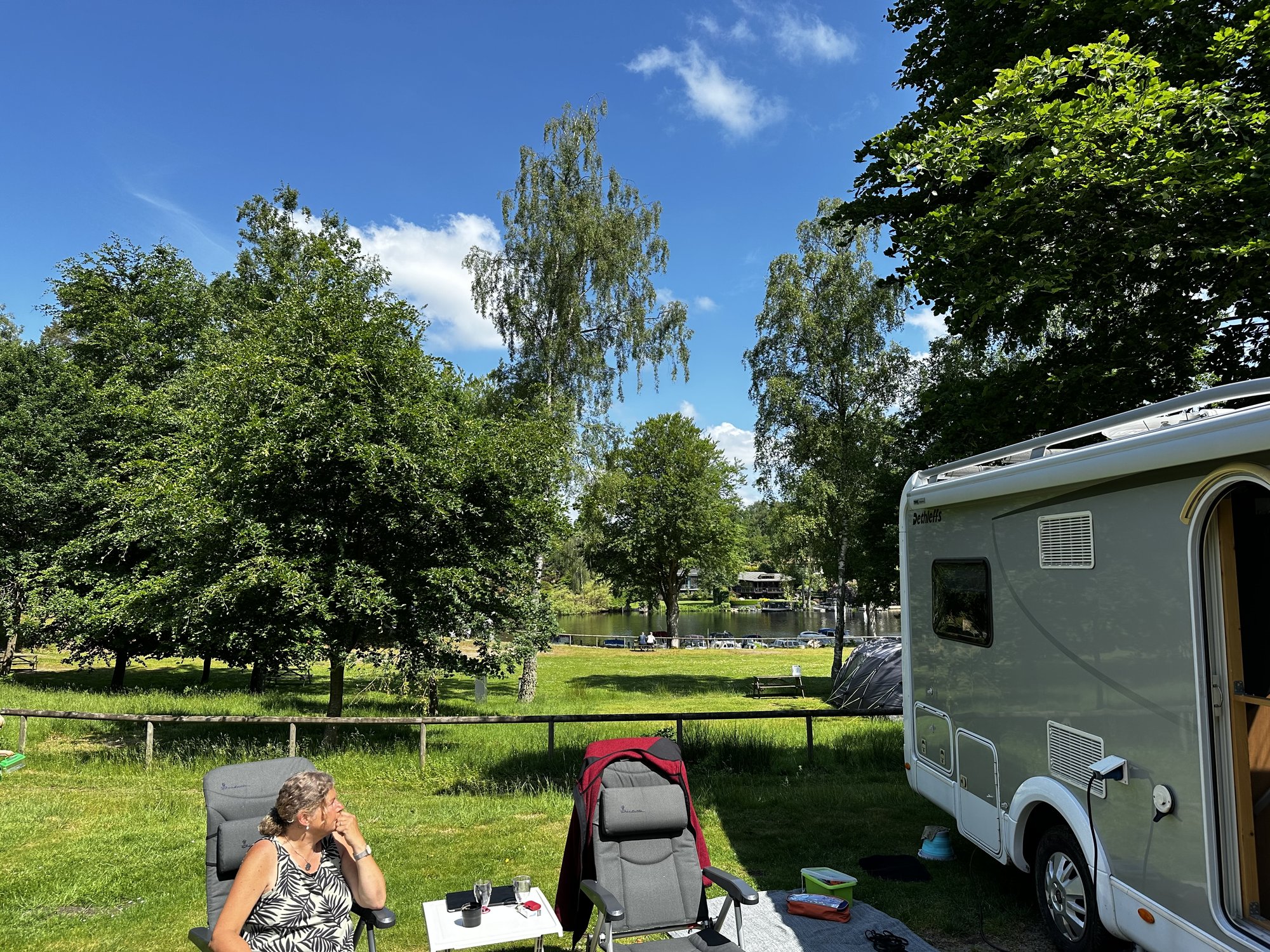Emma auf der Wiesenterrasse mit Blick über den See, Tanja im Campingstuhl