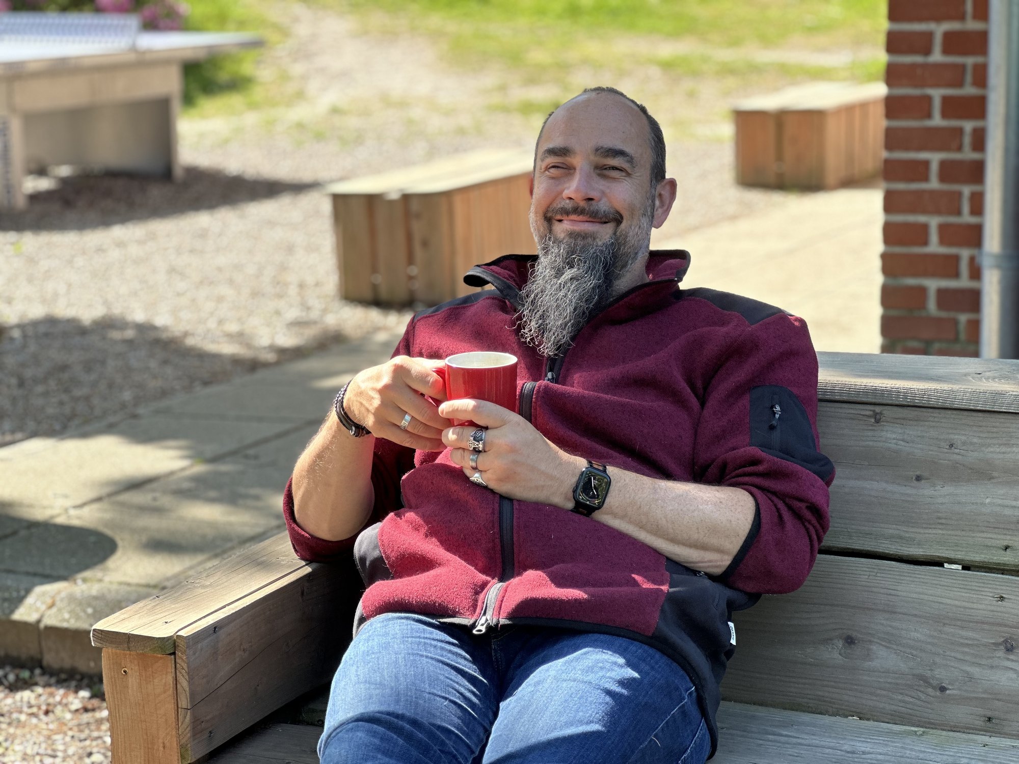 Micha mit rotem Kaffeebecher in der Morgensonne