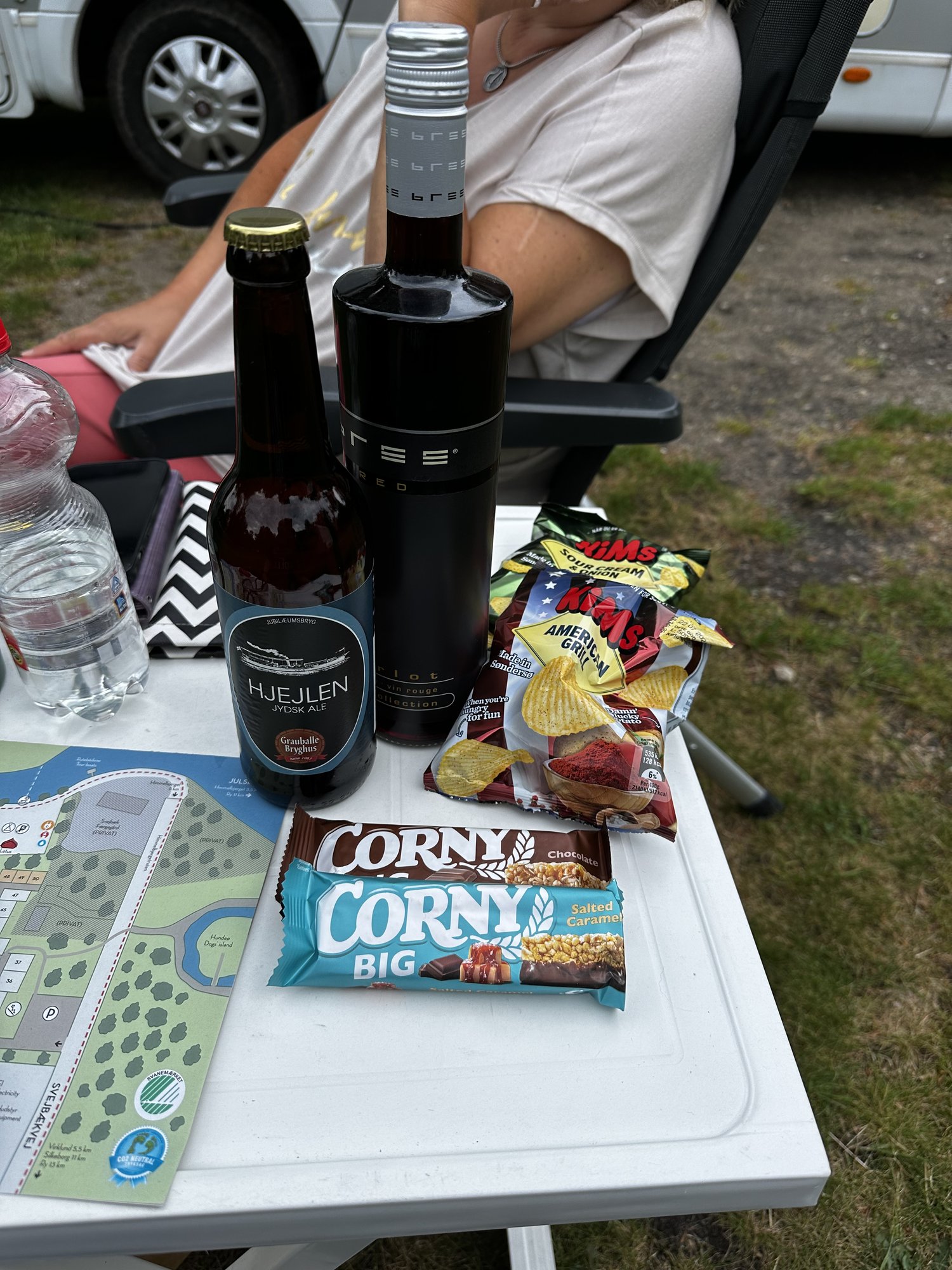 Willkommensgeschenk des Weekend Deluxe: Rotwein, Bier, Chips und Riegel auf dem Campingtisch